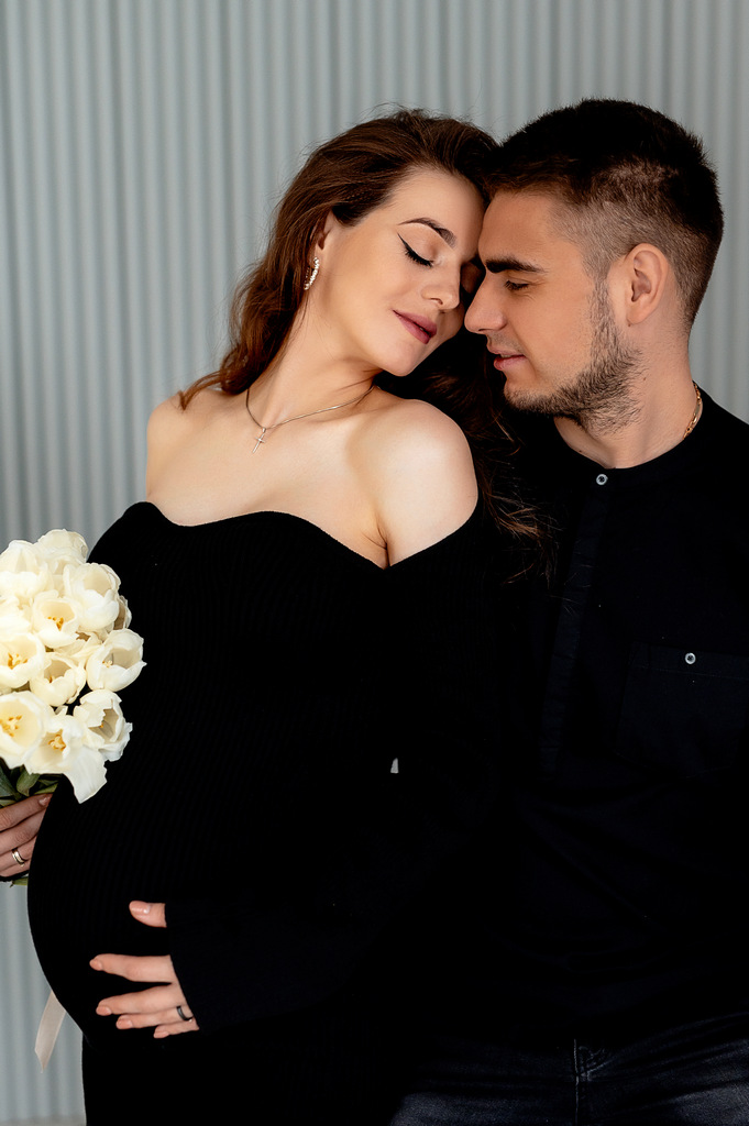 Photoshoot of a pregnant girl with her husband in Krakow. Photoshoot in a dark style in an apartment.